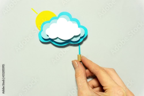 Creative concept flatlay stop motion media video movie footage cloud made of paper with hand switching on weather forecast rain and sun. photo