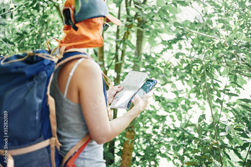 Woman in nature consulting a paper map and mobile phone