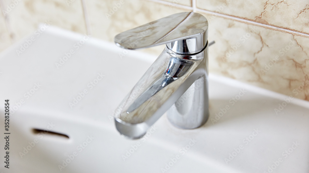 Wasserhahn am Waschbecken in einem Badezimmer Wasserhahn am Waschbecken in einem Badezimmer