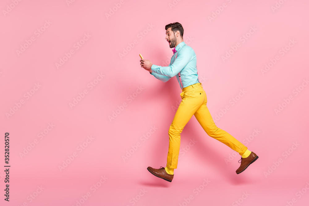 Full length body size profile side view of his he nice attractive cheerful bearded glad guy gentleman jumping running using digital device app 5g discount isolated pink pastel color background