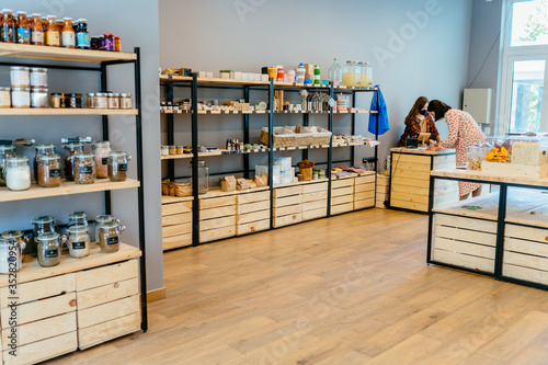 Zero waste shop interior details. Wooden shelves with different food goods and personal hygiene or cosmetics products in plastic free grocery store. Eco-friendly shopping at local small businesses. photo