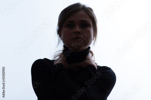 portrait face of young beautiful woman in a black with hands clutching neck, lifestyle 2020 under quarantine and epidemic smothers a person, concept of danger hostage