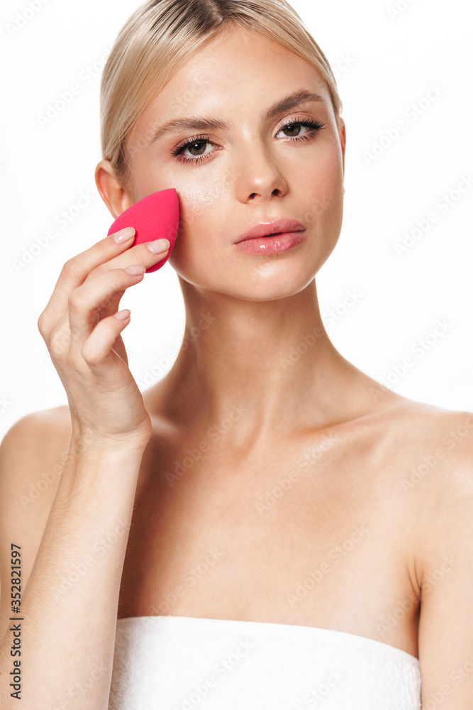 Image of shirtless woman using cosmetic sponge and looking at camera Image of shirtless woman using cosmetic sponge and looking at camera