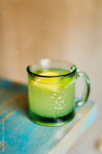 A hot alcoholic drink with mint and lemon in a glass mug