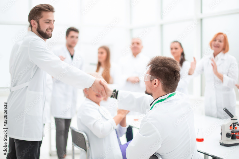 group of scientists congratulating their colleague in the workplace