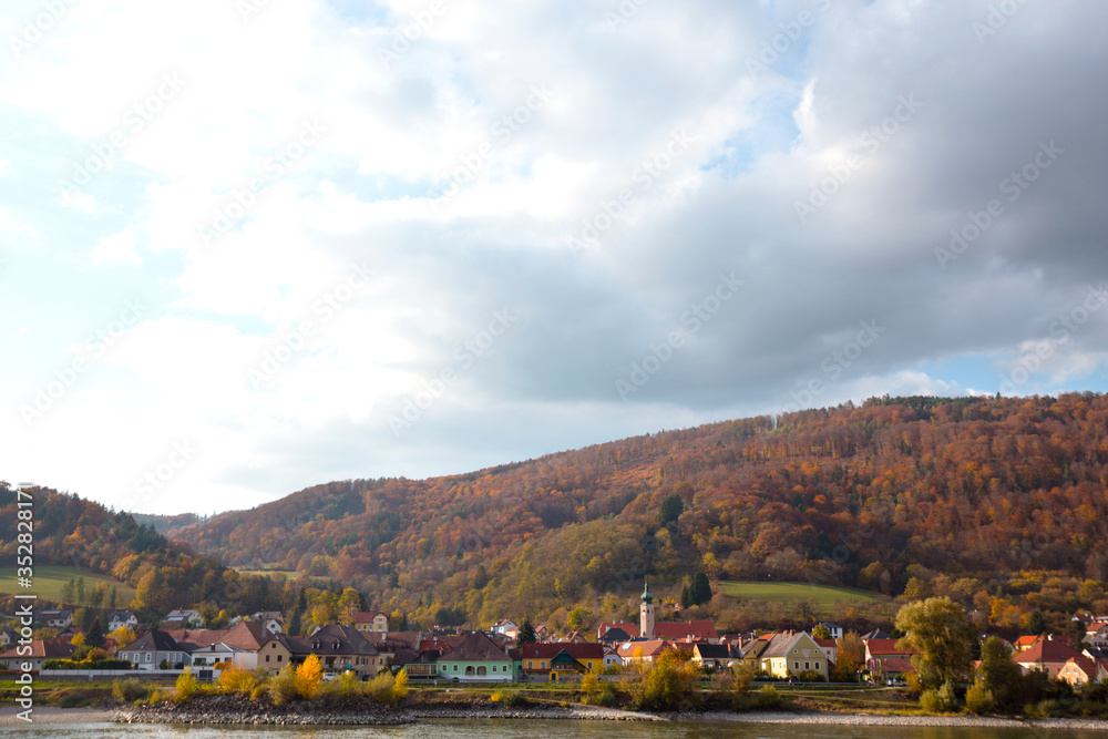 Obraz premium autumn view of small austrian village on a river bank