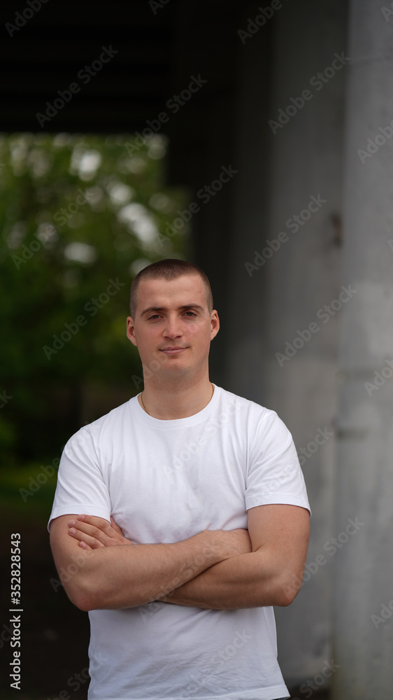 Portrait of a strong young man in a white t-shirt under the bridge Portrait of a strong young man in a white t-shirt under the bridge