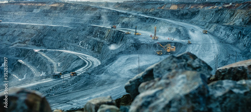 Work of trucks and the excavator in an open pit photo