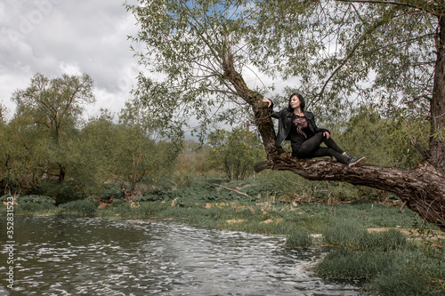 Girl sitting on a tree above the water in the river