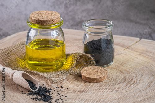 Black cumin seeds with oil on wooden background