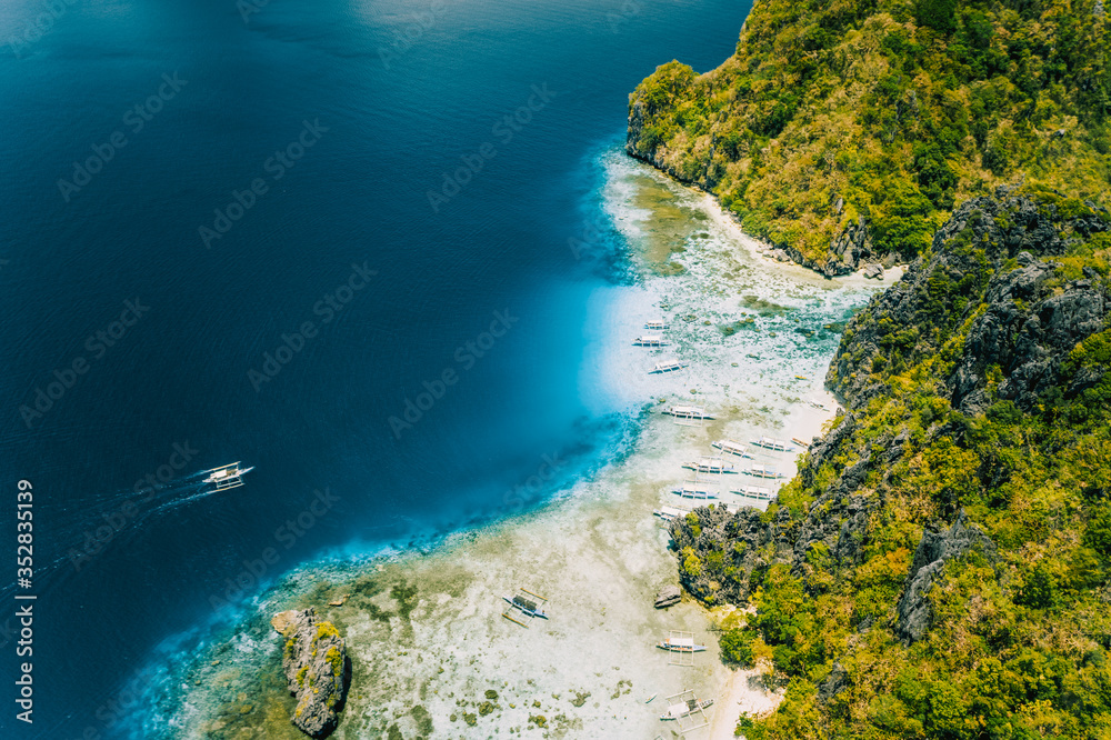 Aerial drone view of tropical Shimizu Island. Limestone coastal rocks, white sand beach in blue water. El Nido, Palawan, Philippines