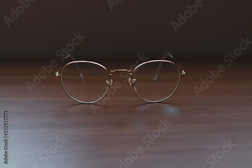 Clear Eyeglasses Glasses with Gold Frame Fashion Vintage Style on Wood Desk Background, Rustic Still Life Style.