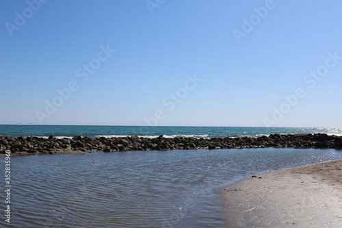 View of beach with stone and blue sea water