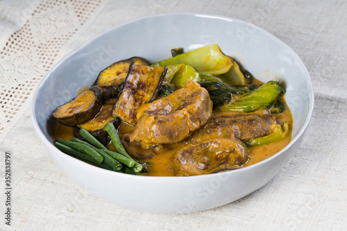 kare kare; a mix of ox tail and tripe with vegetables like eggplant, sitaw (long bean), pechay, puso ng saging stewed in peanut sauce and serve with shrimp paste for additional flavor