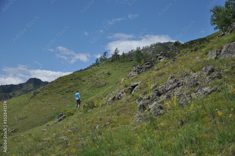 A man in a bright T-shirt climbs up the mountainside