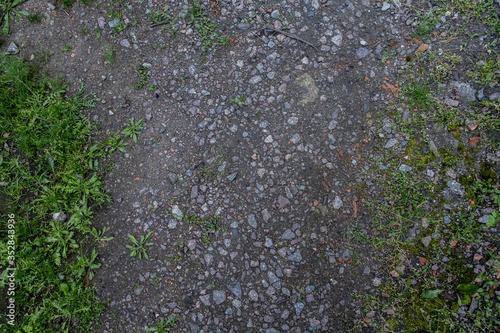 the texture of rural roads with small stones and grass in between the texture of rural roads with small stones and grass in between