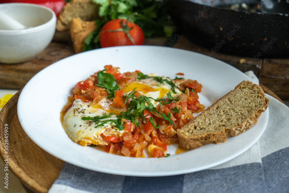 white plate with Israel scrambled eggs shakshuka and dark bread white plate with Israel scrambled eggs shakshuka and dark bread