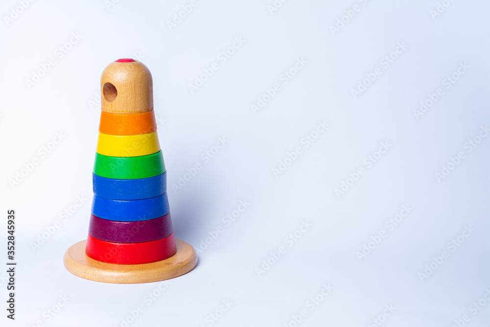 wooden pyramid tower of rainbow blocks stacked on top of each other, on a white background with space for text on the right side of the photo. object placed on the left. horizontal photo orientation wooden pyramid tower of rainbow blocks stacked on top of each other, on a white background with space for text on the right side of the photo. object placed on the left. horizontal photo orientation