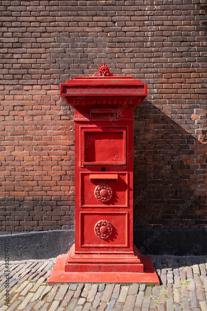 red old Dutch mailbox standing against a brick wall red old Dutch mailbox standing against a brick wall