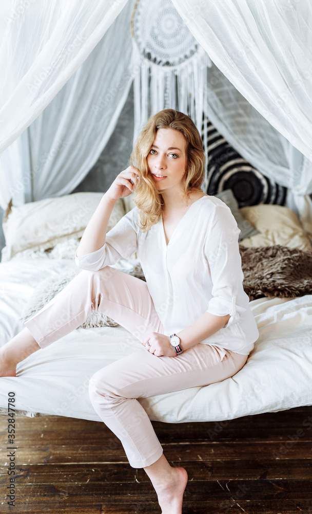 Beautiful blond girl sitting on the sofa in white outfit. Beautiful blond girl sitting on the sofa in white outfit.