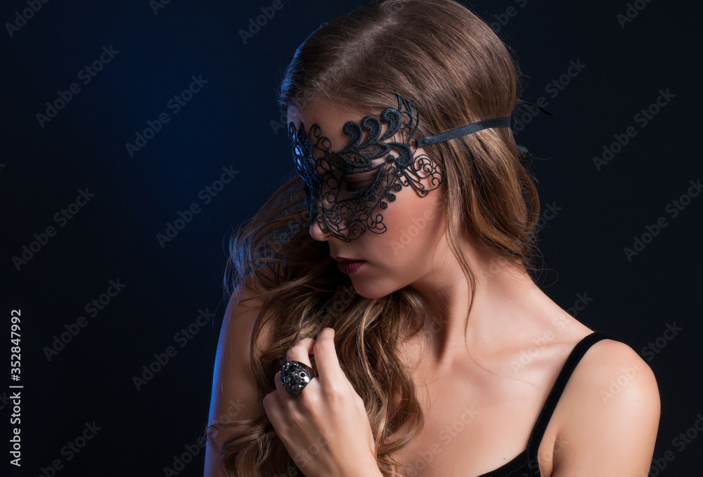 Fototapeta premium young pretty brunette woman in venetian lacy mask. close up portrait lacy mask. red lips make up. erotic passion woman image on black background