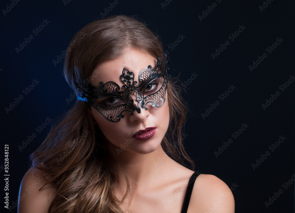 Obraz premium young pretty brunette woman in venetian lacy mask. close up portrait lacy mask. red lips make up. erotic passion woman image on black background