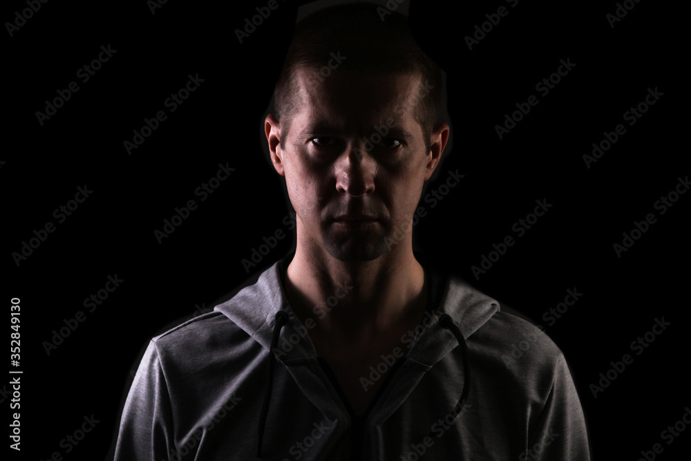 dark silhouette of a man on a black background, a glance at the camera. Dressed in sportswear. Isolated dark silhouette of a man on a black background, a glance at the camera. Dressed in sportswear. Isolated