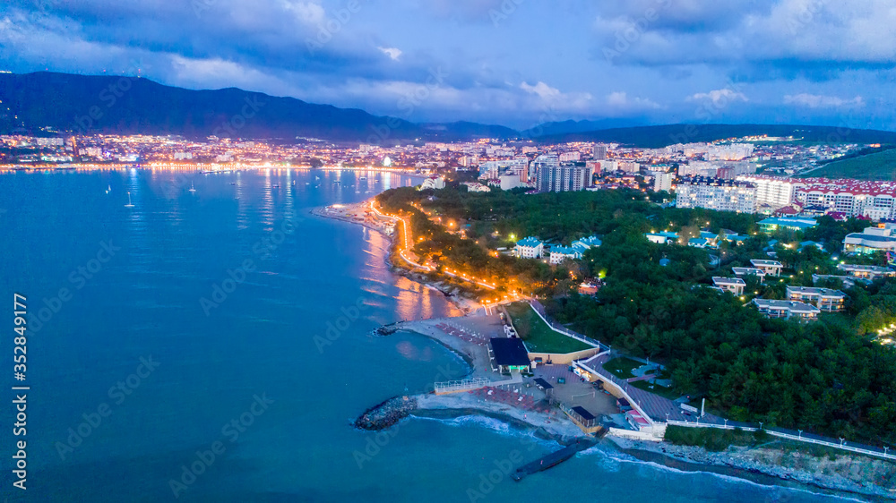 Evening panorama of Gelendzhik resort from a bird's-eye view. The lights of the embankment are reflected in the dark blue water
