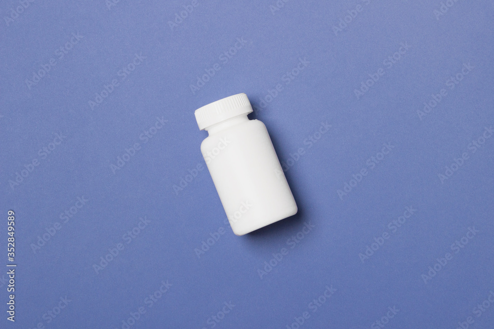 White plastic medical container for pills on blue background White plastic medical container for pills on blue background