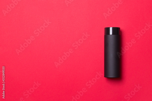 black thermos cup on red colored paper background background with copy space