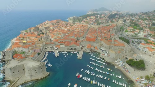 Aerial shot of old town by blue ocean, drone is flying forward over sea - Dubrovnik, Croatia photo