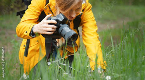 Close-up of female photographer making macrography using dslr camera kneeling in spring nature photo