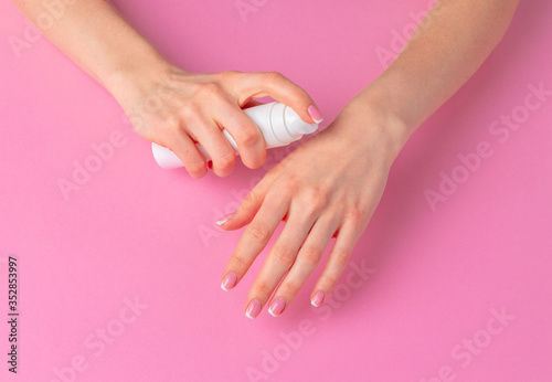 Female hand holding skincare product bottle on pink