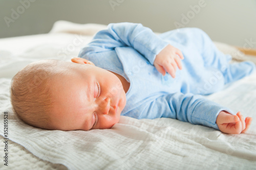 Newborn sleeping close up. Baby is sleeping soundly on the bed and copy space. Infant care, colic, sleep after bath.