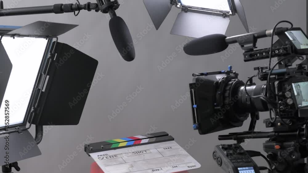Push in and pull out shot moving through a professional video production film set with camera, lights, and microphone all set up for an interview in a studio setting.