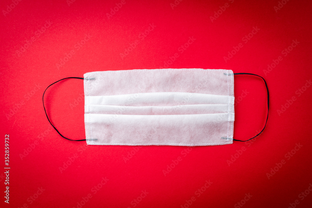 Obraz premium Medical mask on red background. Coronavirus disease COVID-19.