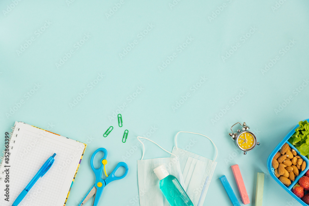 School the new reality global pandemic coronavirus covid-19 to school, tools, notebook, medicine mask, sanitizer, school lunch box  on blue background, stylish banner flyer, flat lay, top view