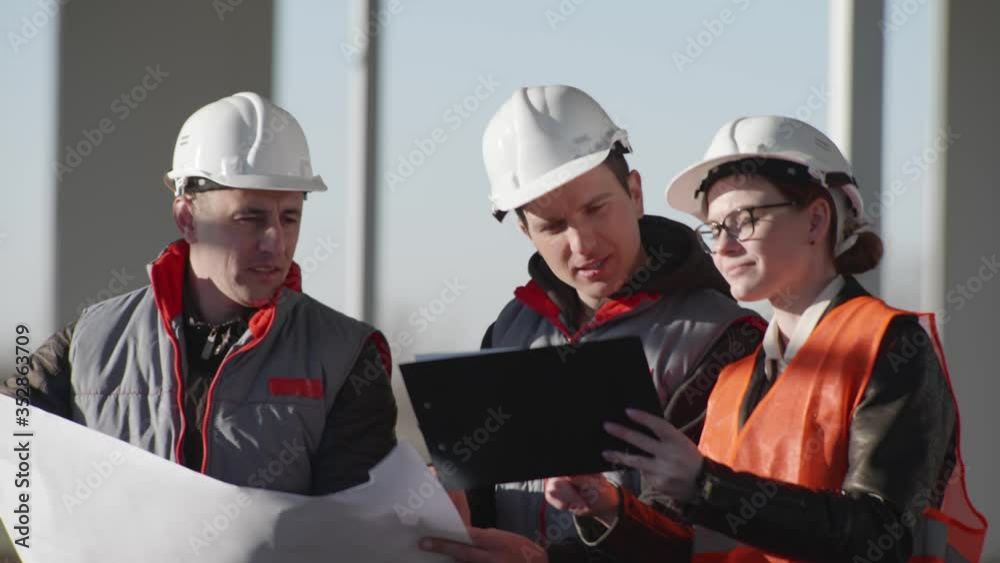 development, team development specialists in protective helmets discuss drawings at the construction site of an indoor building development, team development specialists in protective helmets discuss drawings at the construction site of an indoor building
