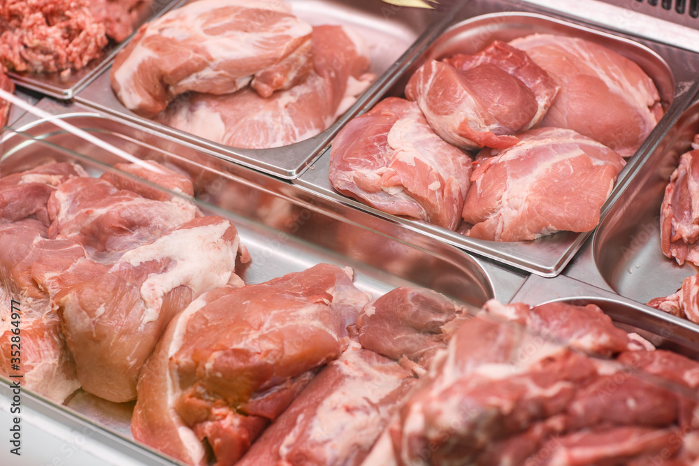 Heap of fresh meat food meat food background in supermarket store. Different types of raw meat in plastic boxes, leg of lamb on the bone, beef tail, beef neck, beef blade. Concept of farm and raw