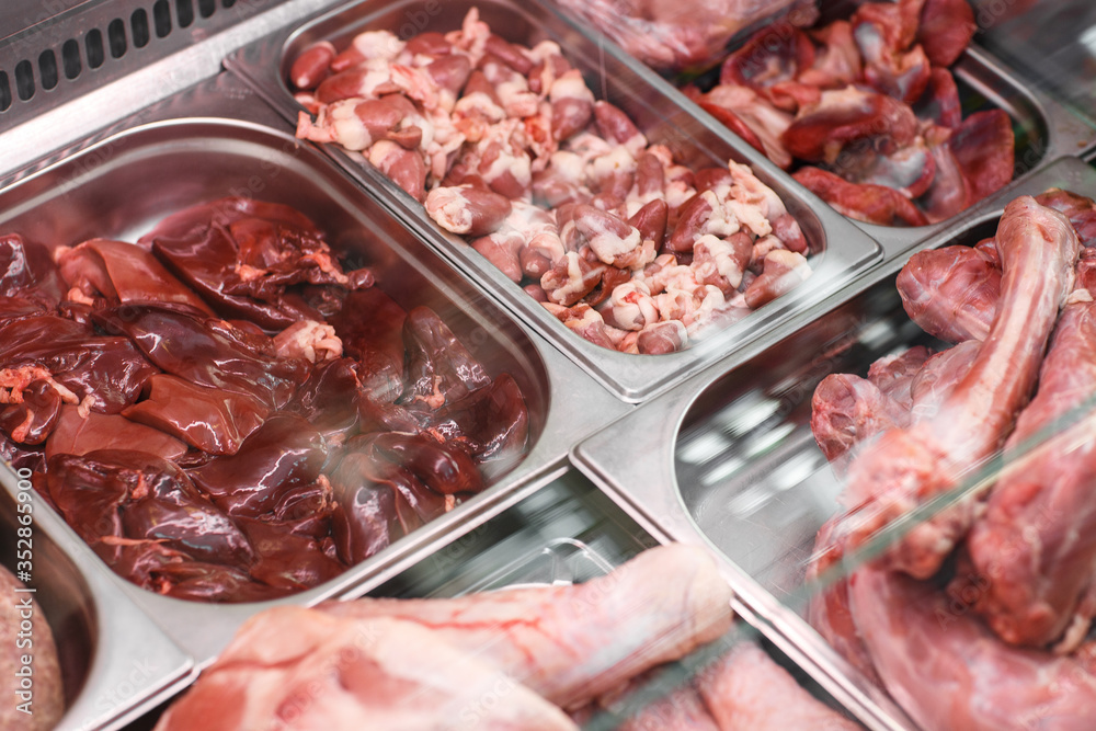Heap of fresh meat food meat food background in supermarket store. Different types of raw meat in plastic boxes, leg of lamb on the bone, beef tail, beef neck, beef blade. Concept of farm and raw