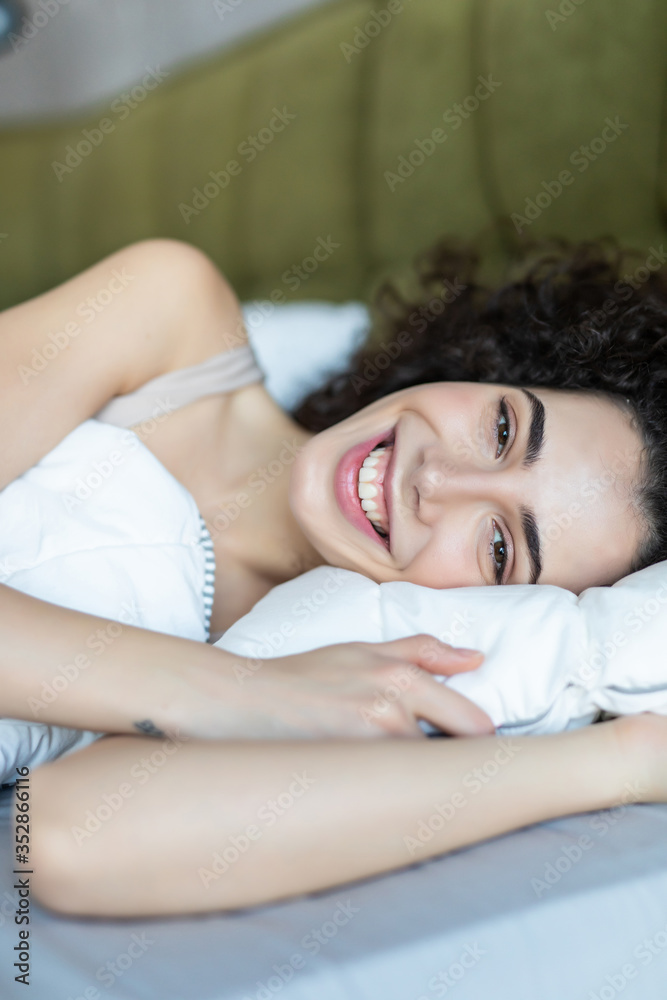 Obraz premium Smiling woman lying in her bed in bright bedroom