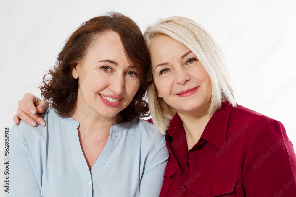 Happy menopause concept. Two healthy and beautiful middle aged women isolated on white background. Woman support woman. Closeup faces and skincare makeup. Happy menopause concept. Two healthy and beautiful middle aged women isolated on white background. Woman support woman. Closeup faces and skincare makeup.