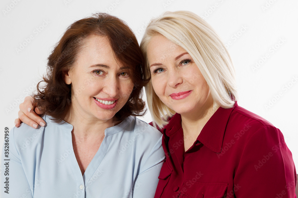 Happy menopause concept. Two healthy and beautiful middle aged women isolated on white background. Woman support woman. Closeup faces and skincare makeup. Happy menopause concept. Two healthy and beautiful middle aged women isolated on white background. Woman support woman. Closeup faces and skincare makeup.