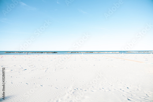 Slightly overexposed shot of a beach in the Italian Adriatic Riviera Romagnola area, noby around due to covid. Flat horizon, minimal and absence consepts. Desolation yet positivity. photo
