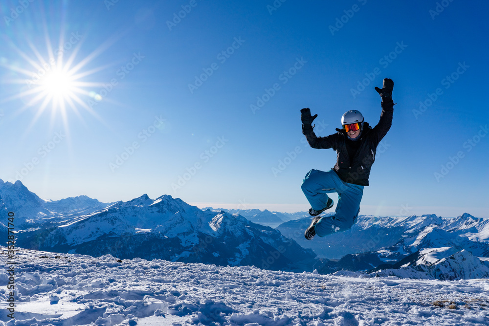 Girl with goggles and helmet is leaping midair in winter.