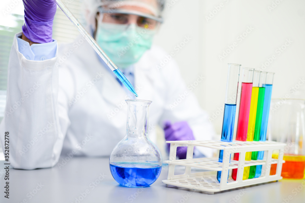 Young doctor scientist in the laboratory making experience research about covid19 coronavirus vaccine wearing white lab coat a mobcap and surgical mask Young doctor scientist in the laboratory making experience research about covid19 coronavirus vaccine wearing white lab coat a mobcap and surgical mask