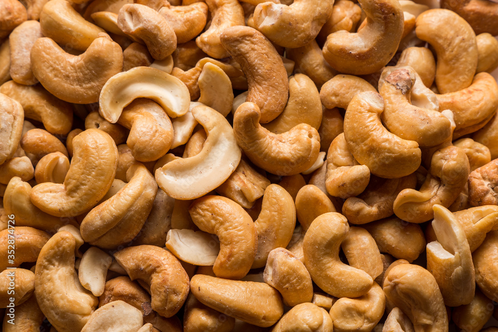 Whole roasted cashew nuts background. Vegetarian healthy snack. Organic food. Vegetable diet. Top view. Whole roasted cashew nuts background. Vegetarian healthy snack. Organic food. Vegetable diet. Top view.