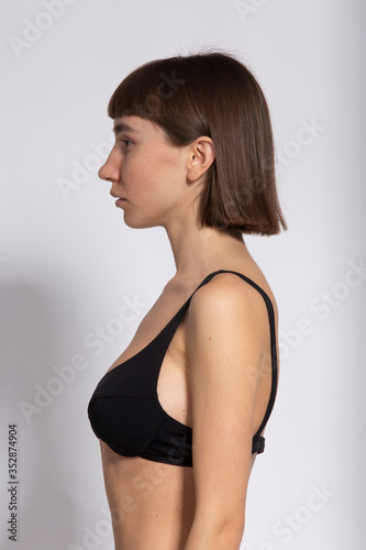 profile shot of pretty model with her hair behind the ears isolated on white in black bra