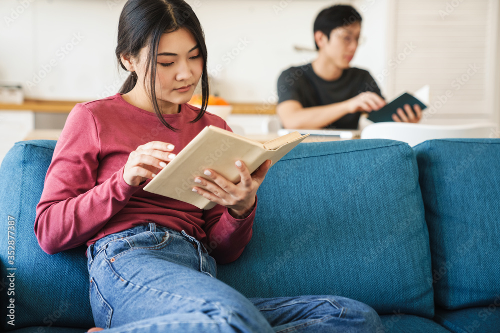 Obraz premium Photo of young concentrated asian couple reading books while sitting