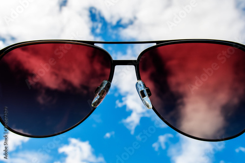 A look at the sky through sunglasses. Blurred blue sky and white clouds. Close up.